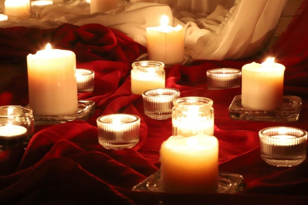 Several lit candles on a red cloth