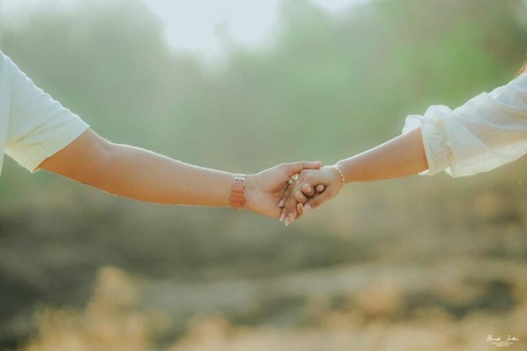 Two hands gently holding each other outdoors