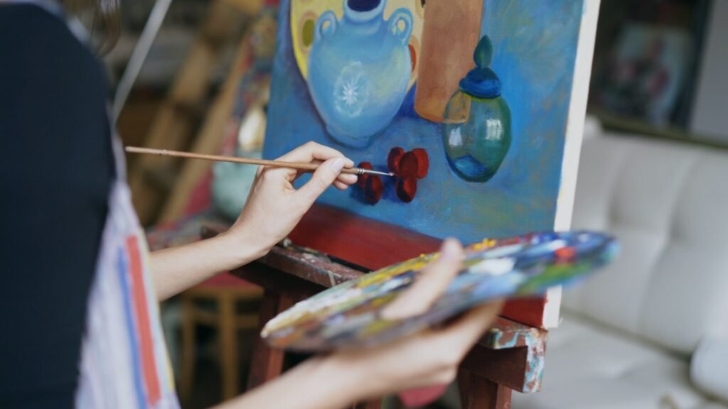 Artist painting still life on canvas with palette.