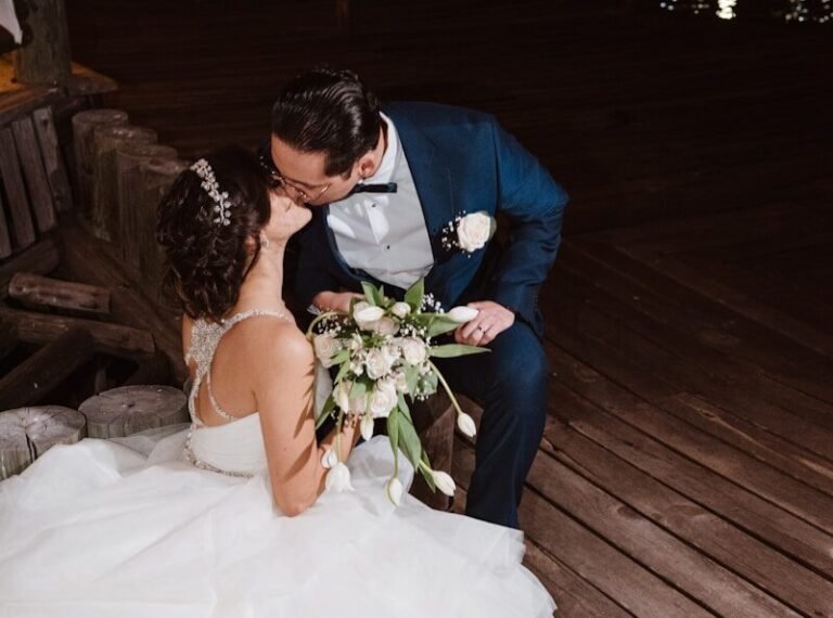 Newlyweds kissing on a wooden dock at night