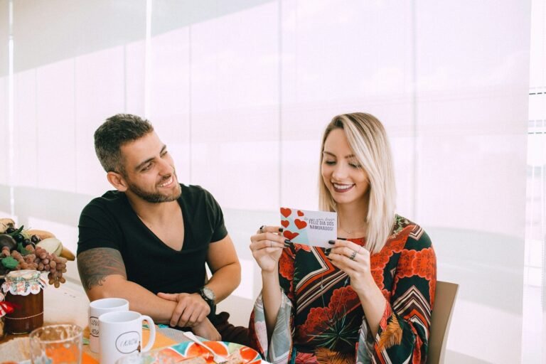 man in black crew neck t-shirt sitting beside woman in orange and blue floral dress