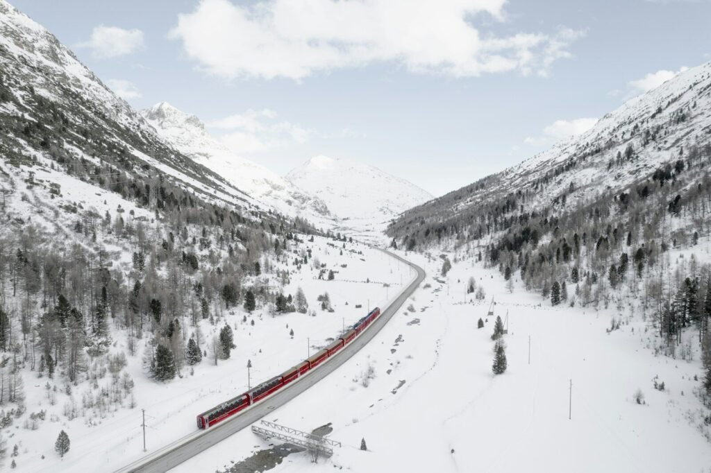 a red train traveling through a snow covered mountain