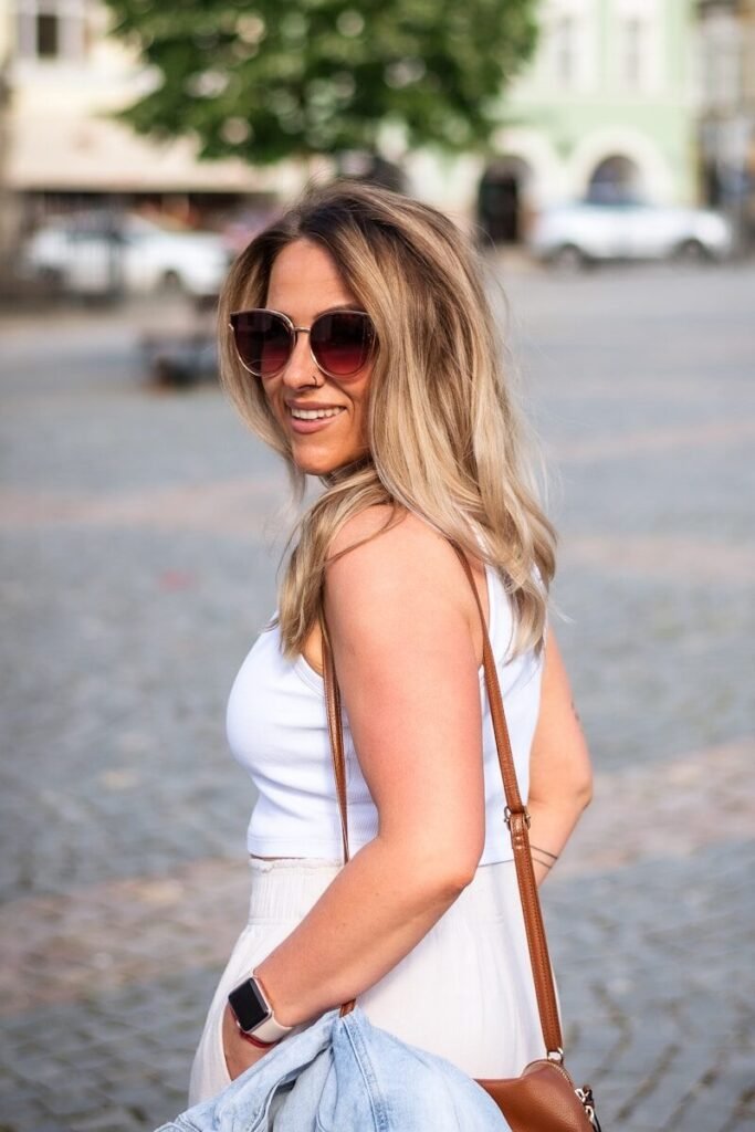 a woman in a white dress carrying a brown purse