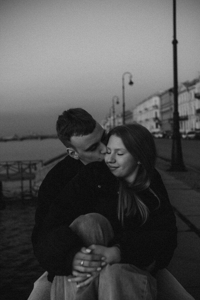 A couple embracing by the water at dusk