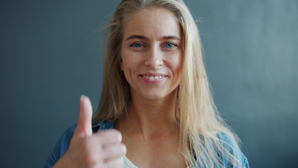 Young woman smiling and giving a thumbs up.