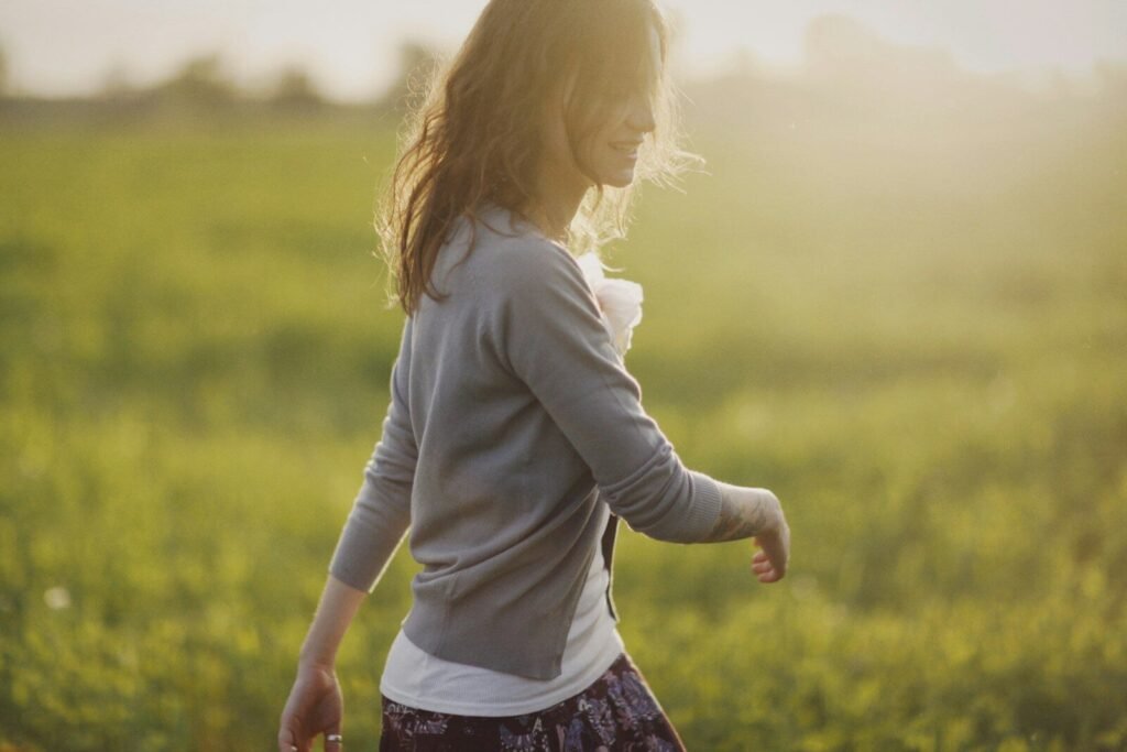 a young girl walking through a green field