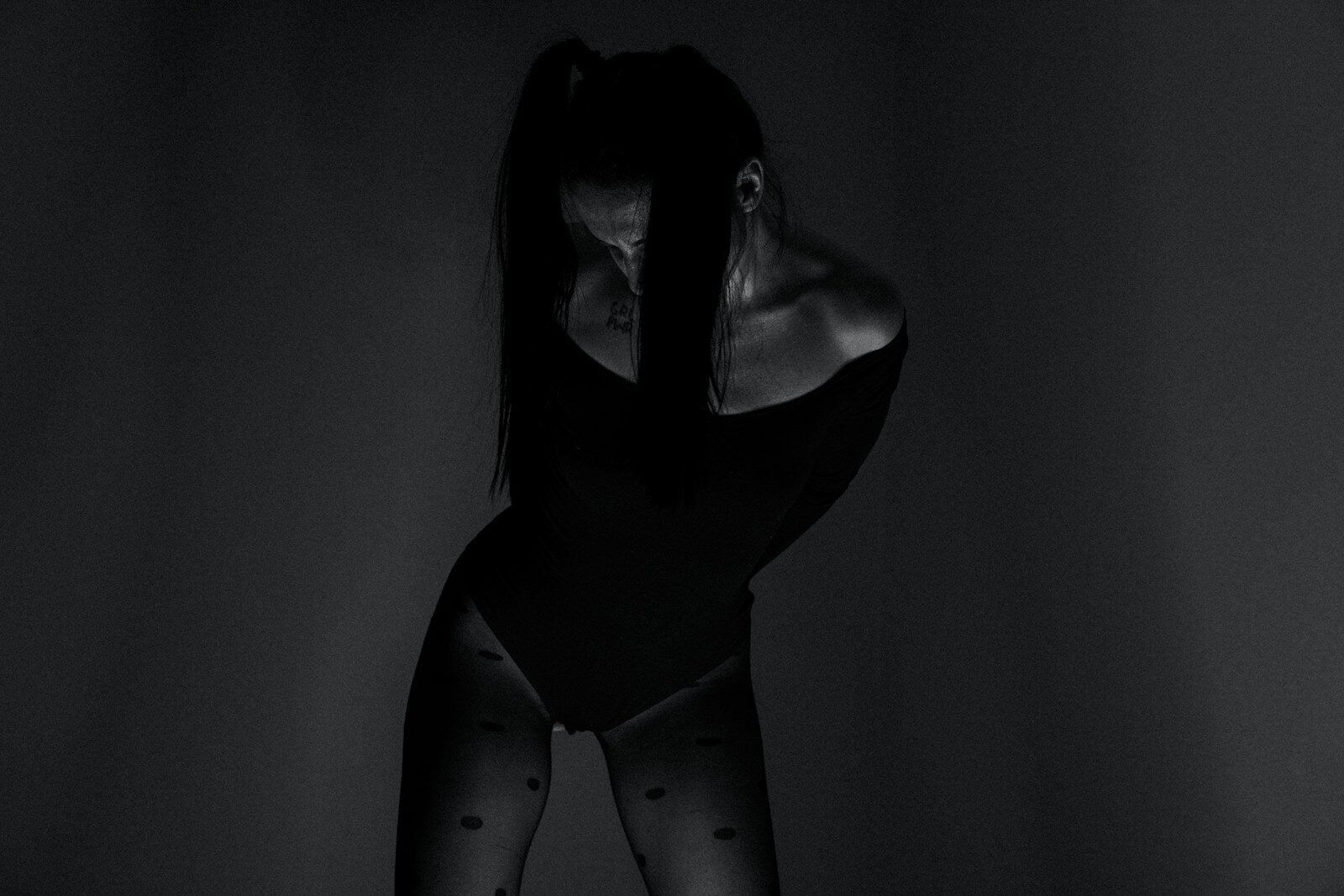 a woman in a black bodysuit with polka dots on her tights