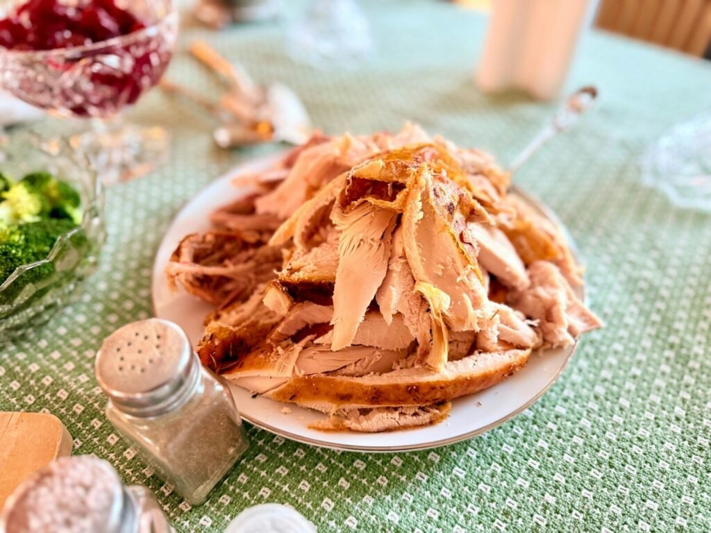 A plate of carved turkey sits on a table.