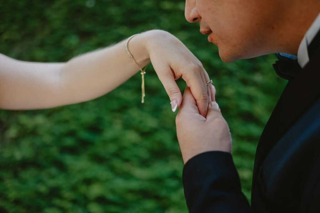 Man kissing woman's hand with greenery background
