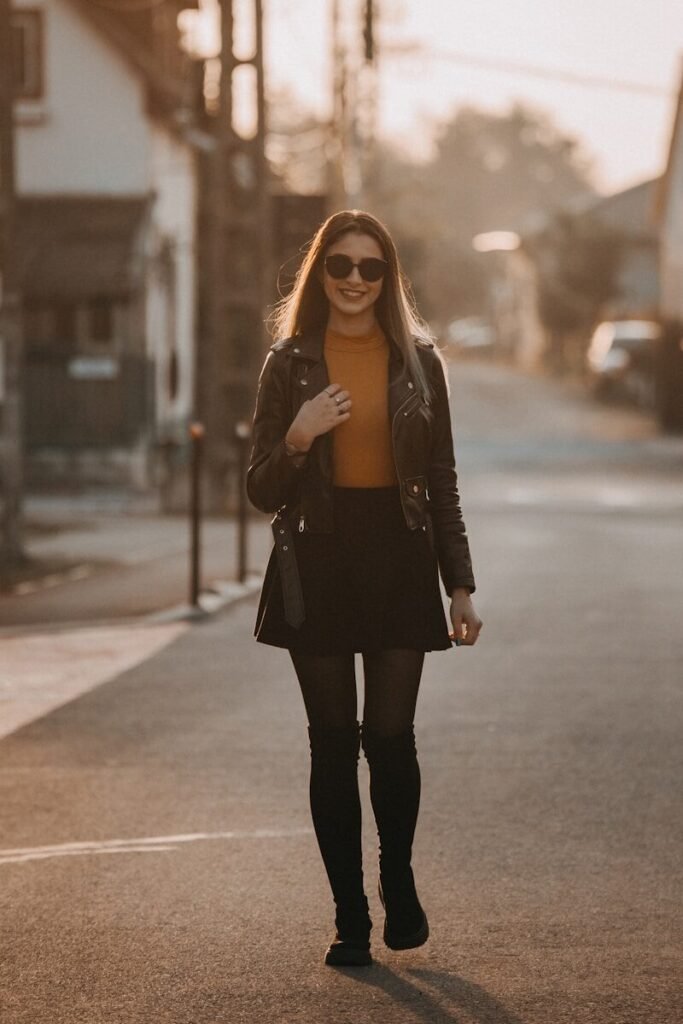 A young woman walks down a street at sunset.
