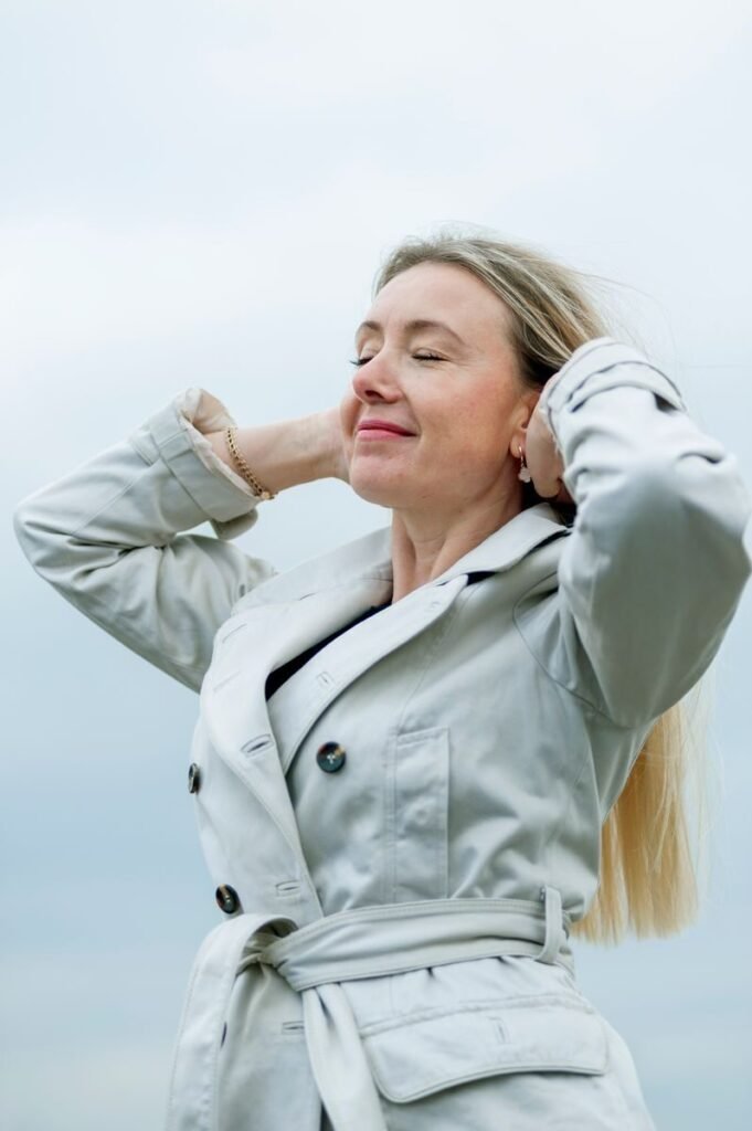 Woman enjoying a serene outdoor moment with closed eyes and relaxed posture.