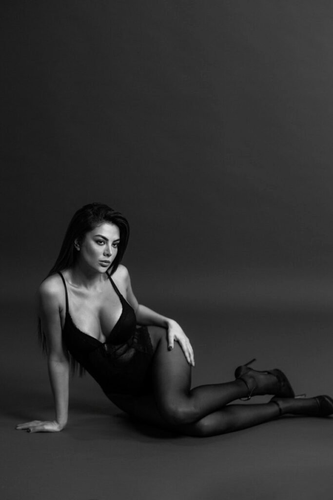 Woman in black lingerie and heels poses.