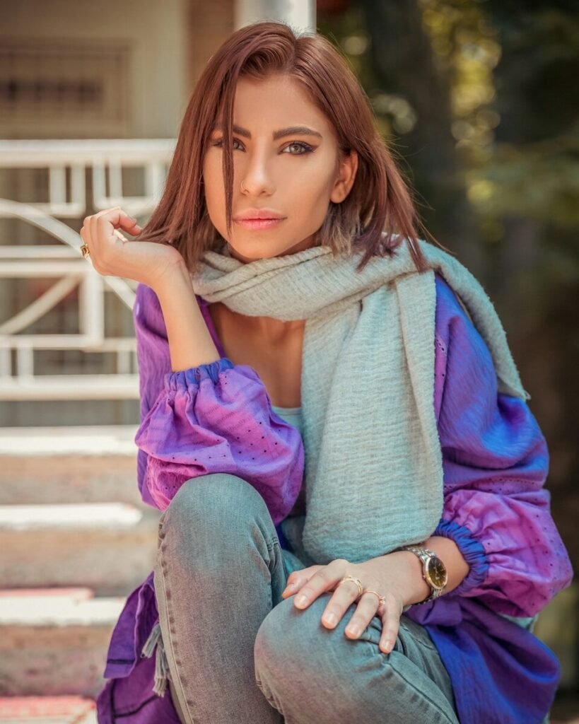 a woman sitting on steps with a scarf around her neck