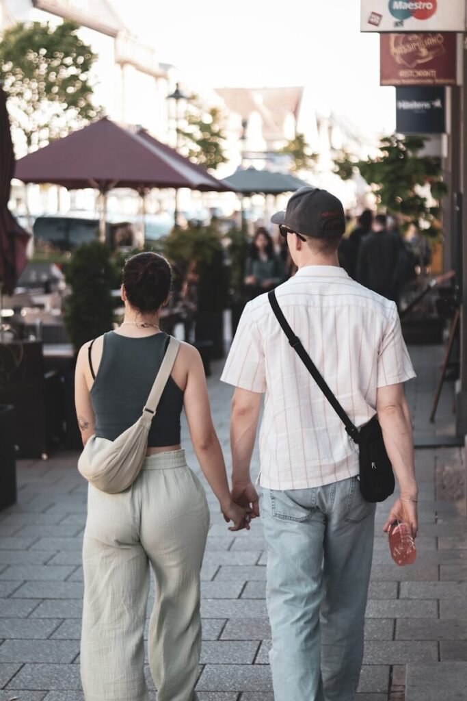 a man and woman walking down a sidewalk holding hands