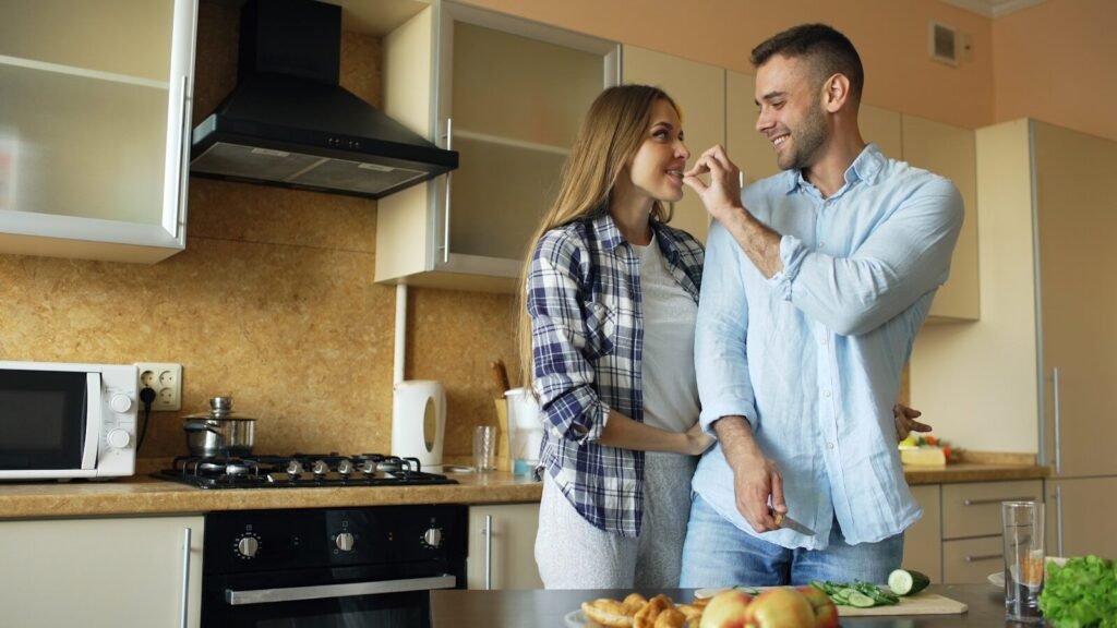 Couple feeding each other in a kitchen.