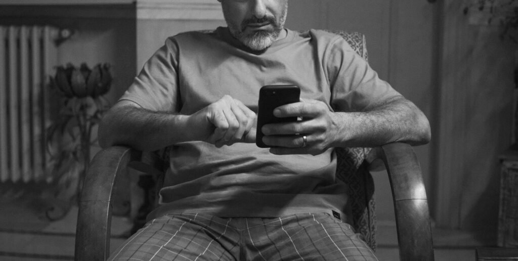A man sitting in a chair looking at his cell phone