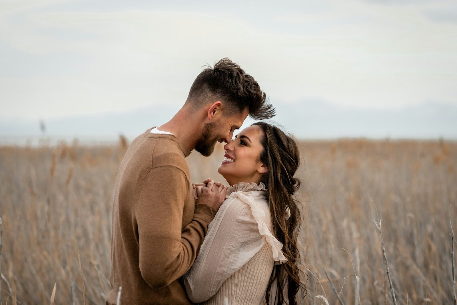 Couple looks at each other lovingly in a field.