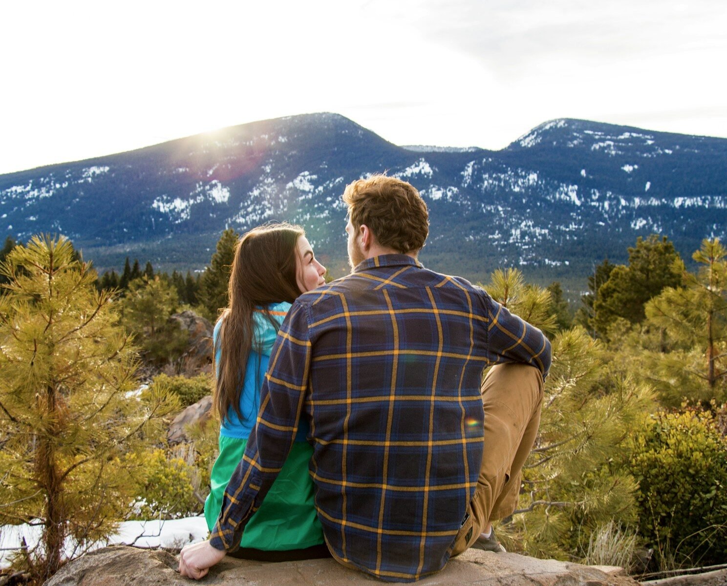 man and woman sitting on rack facing at mountain