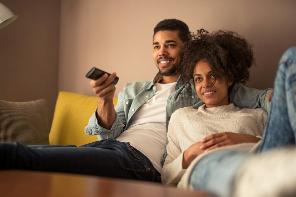 a man and a woman sitting on a couch looking at a cell phone