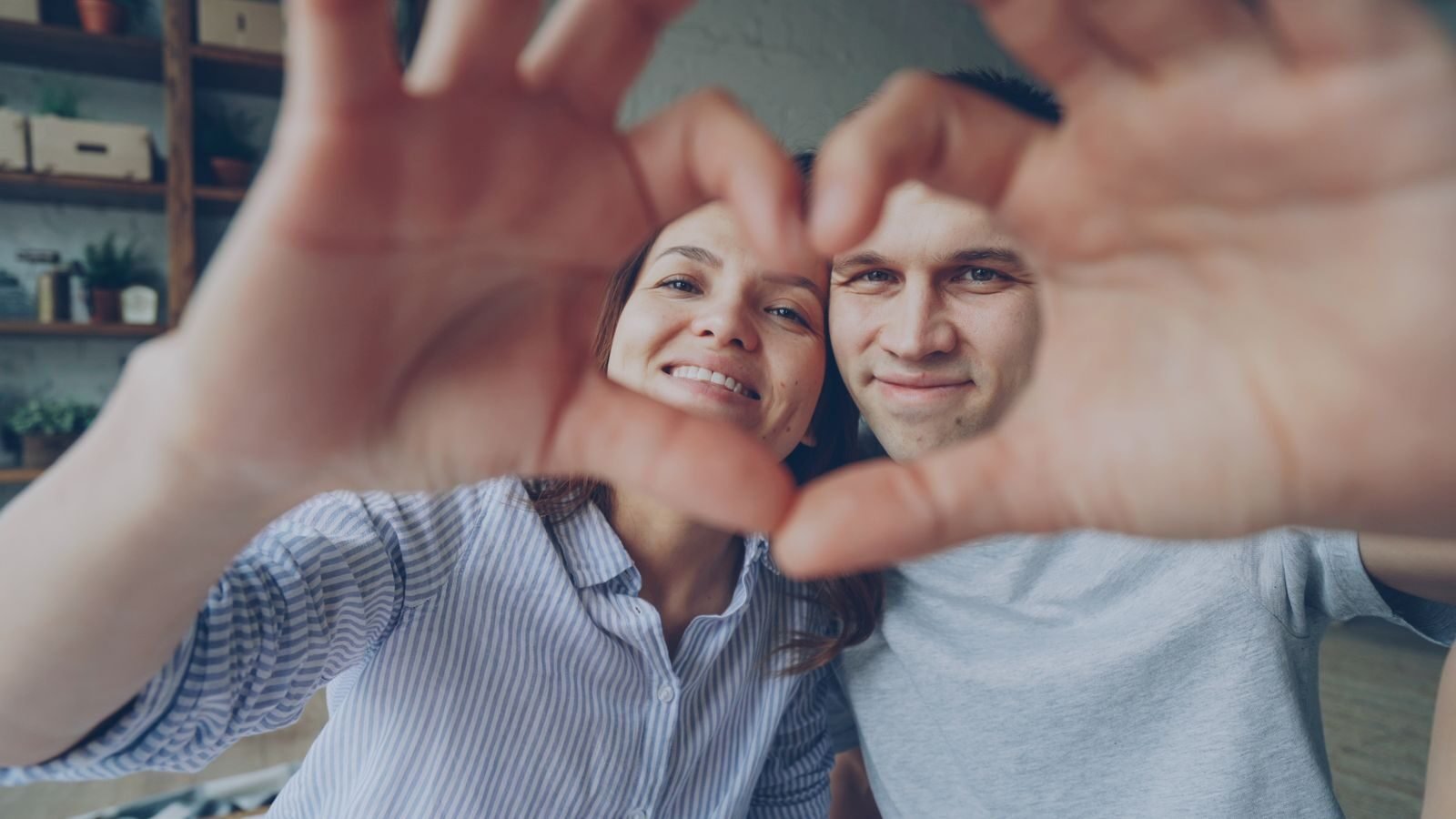 Happy couple forming heart shape, symbolizing love and connection.