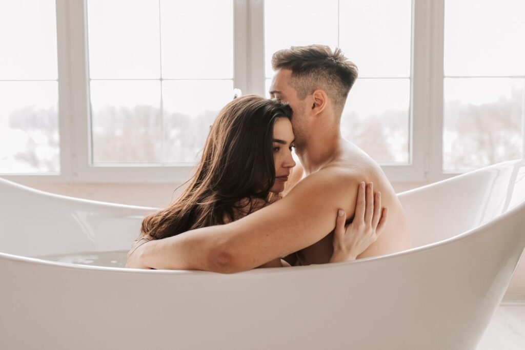 An intimate moment between a couple in a modern bathtub indoors.